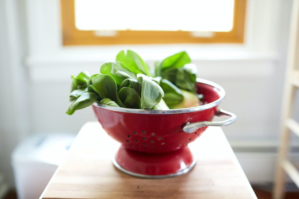 red colander with spinach in
