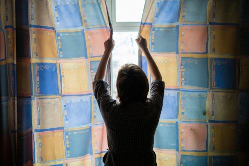 girl drawing curtains in her student accommodation