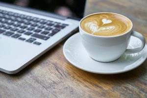 Coffee on a table next to a laptop 
